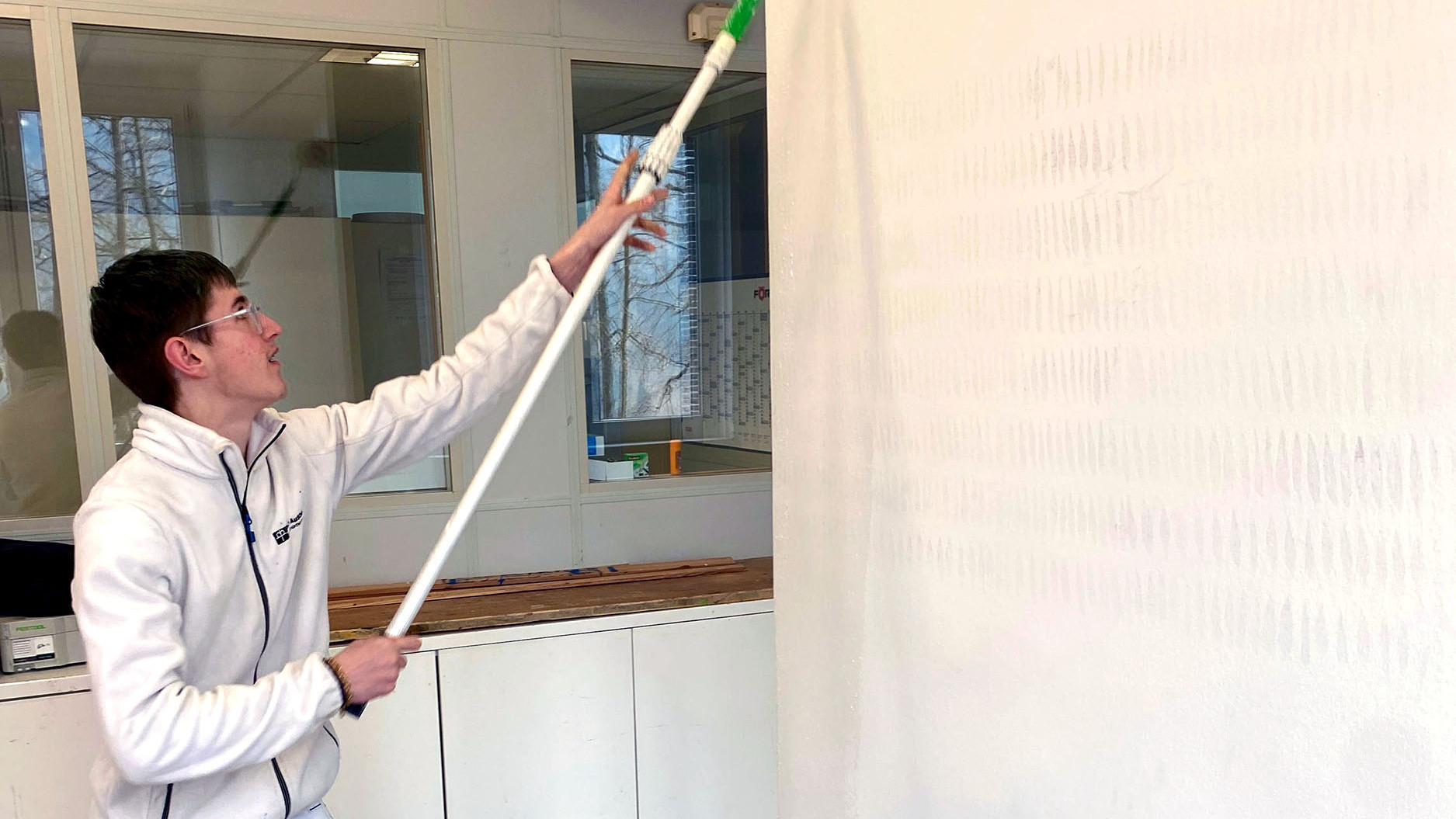 Ein junger Mann streicht eine Wand.