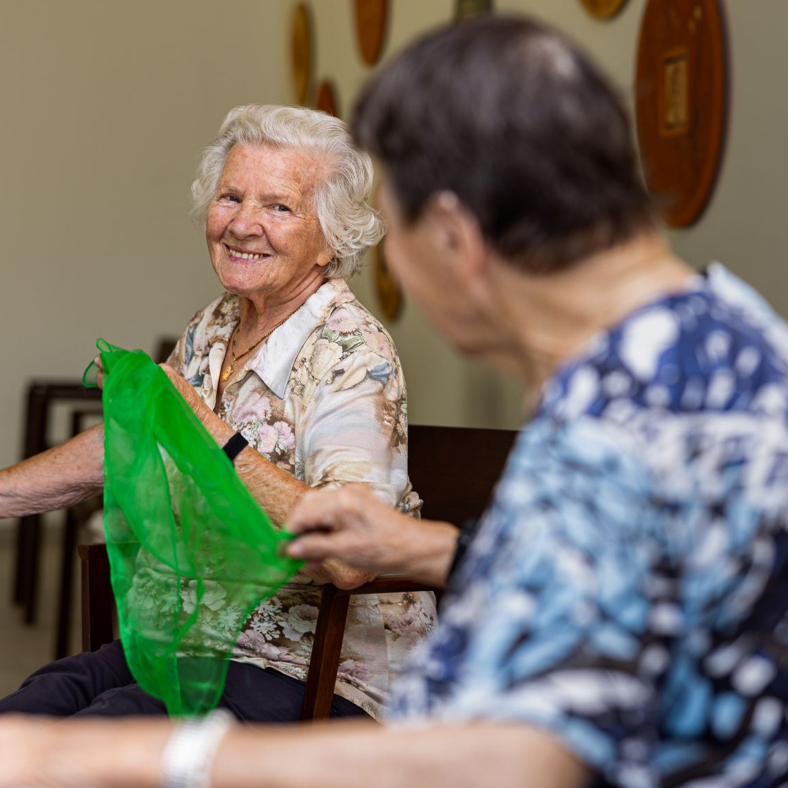 Zwei sitzende Frauen spielen mit einem grünen Tuch