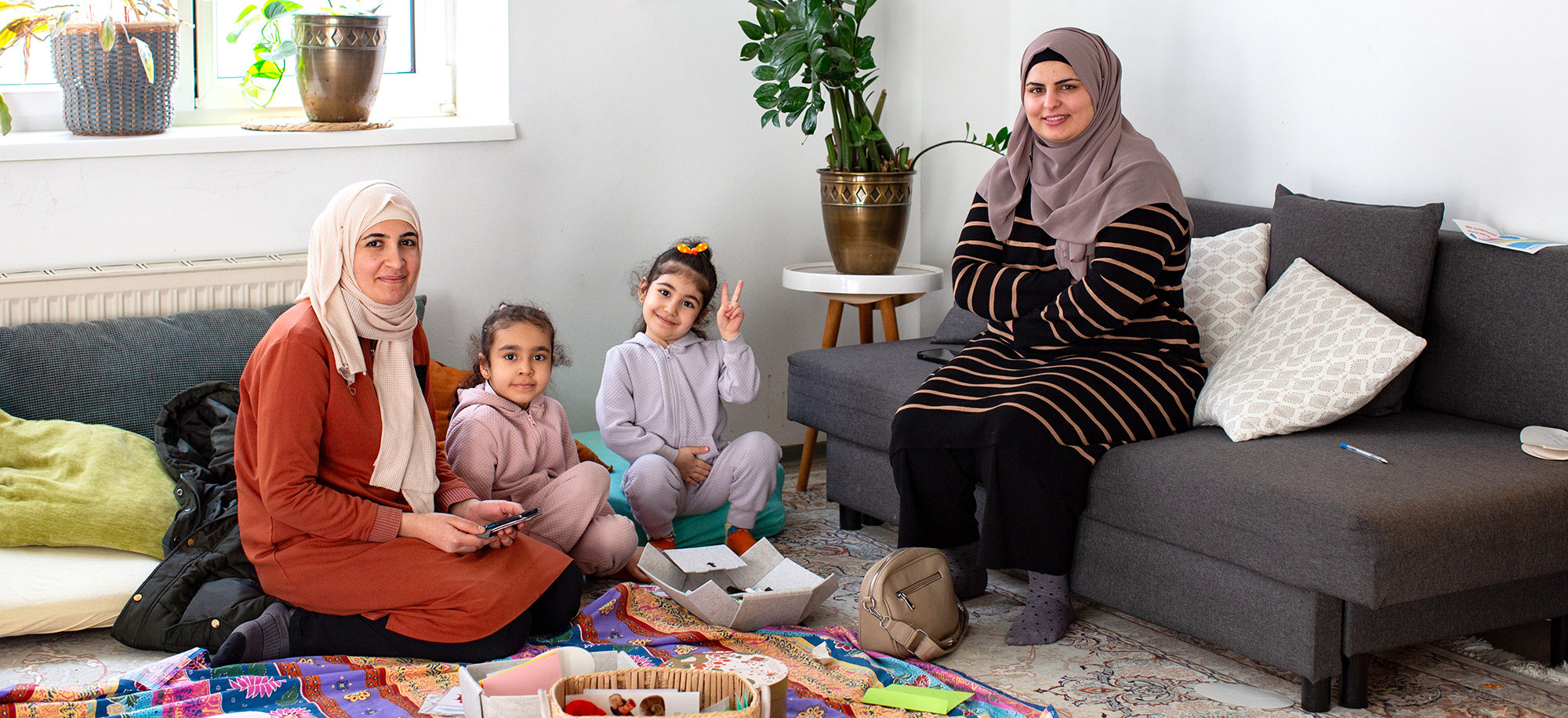 Zwei Frauen sitzen mit ihren Kindern auf dem Teppichboden im Frauencafe der Diakonie Frauenberatung