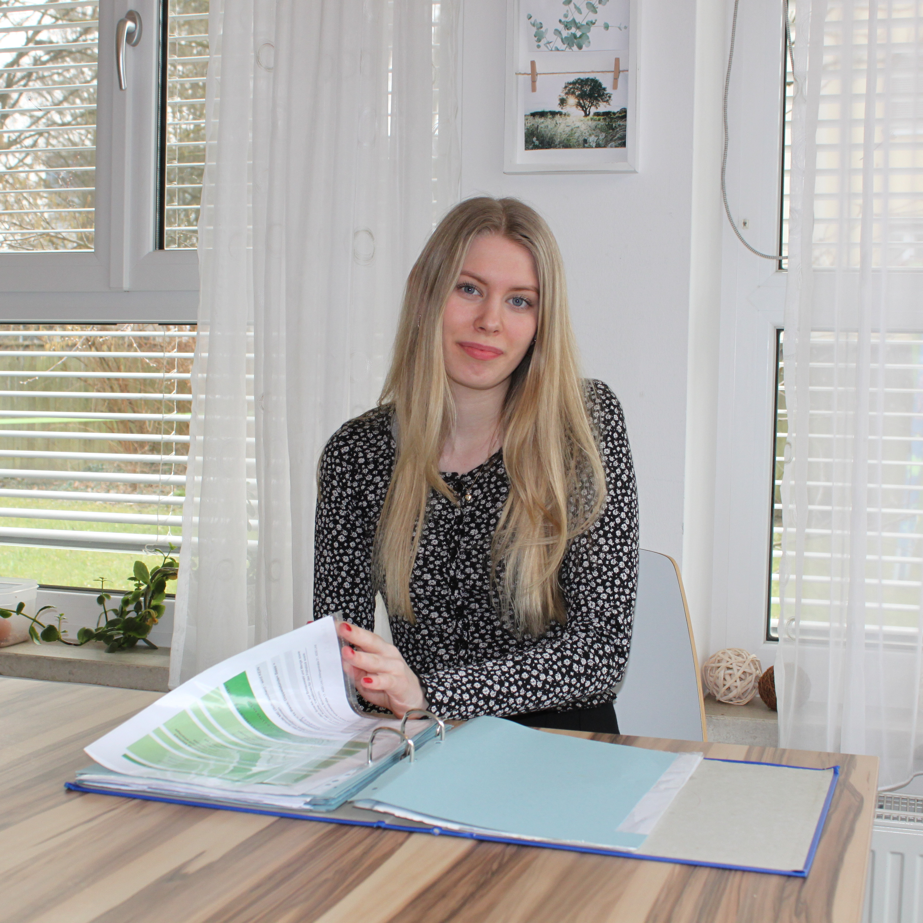 Elisa sitzt an einem Tisch in der WG Kaya der Diakonie und blättert in einem Ordner.