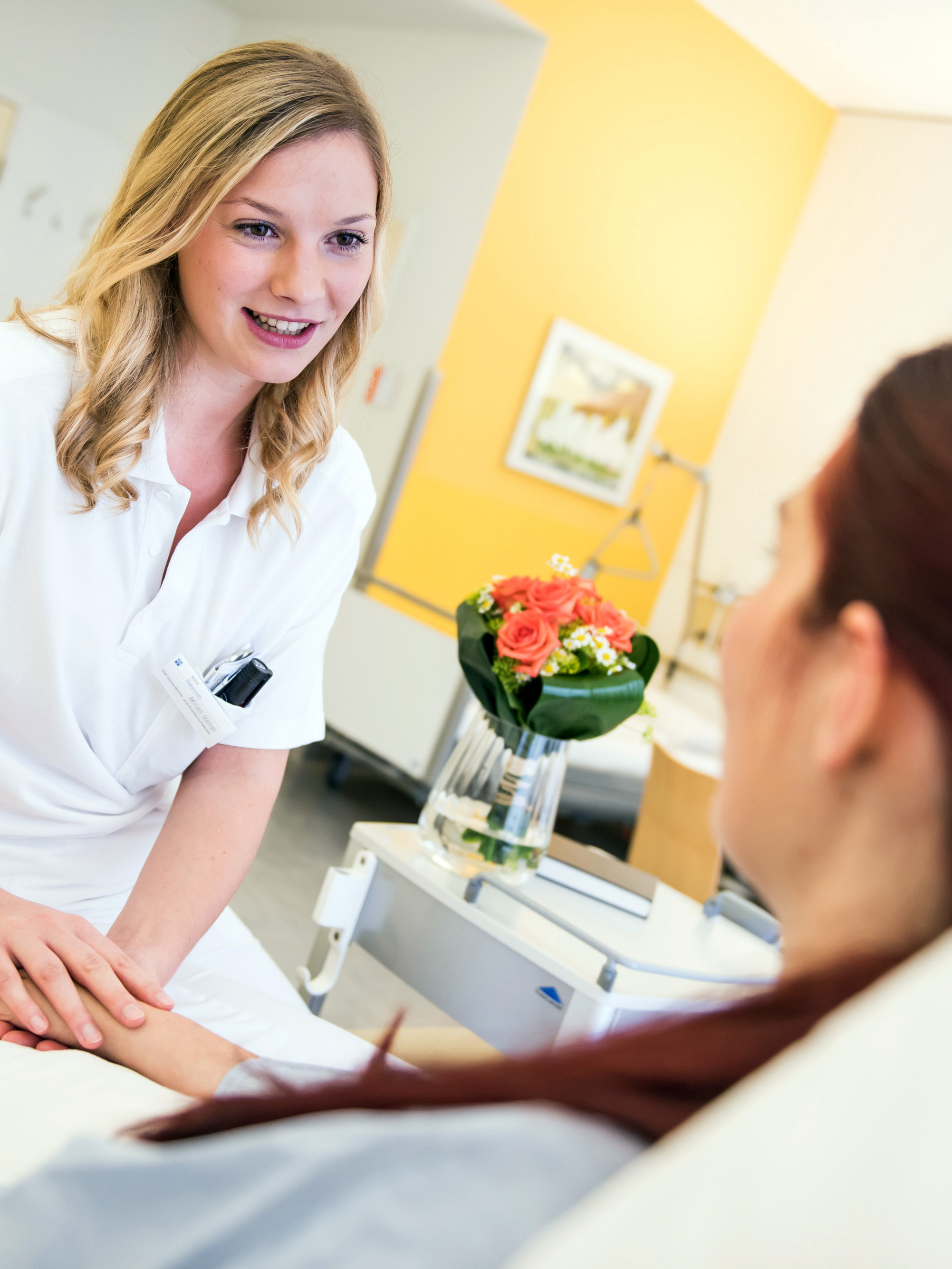 Eine diplomierte Gesundheits- und Krankenpflegerin mit einer Patientin im Zimmer
