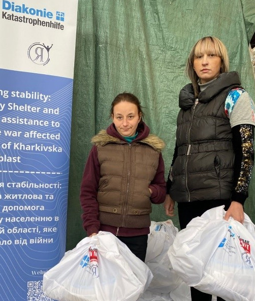 Zwei Frauen mit großen, weißen Plastiktüten in den Händen.