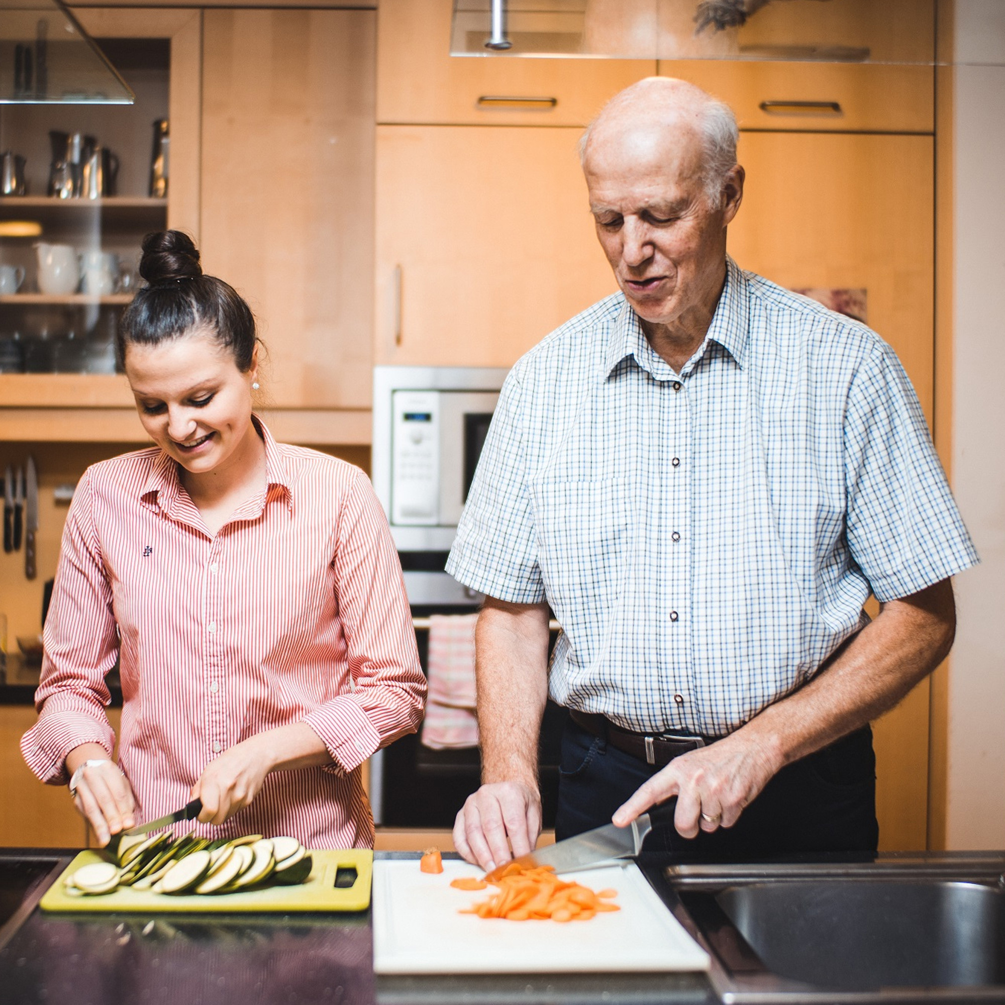 Eine junge Frau und ein älterer Mann kochen gemeinsam.