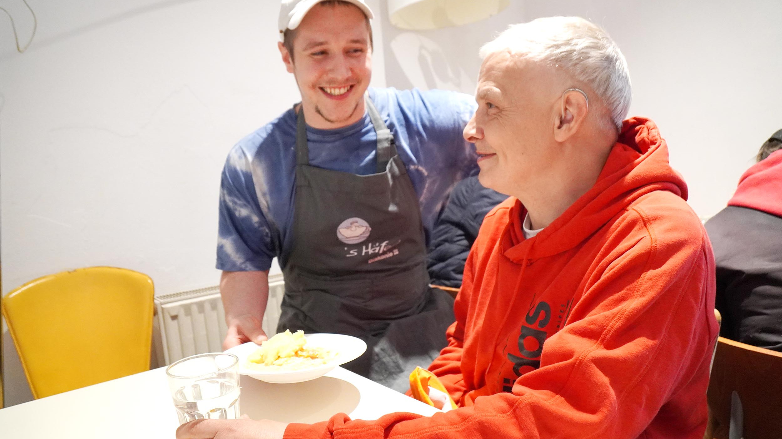 Foto eines Koches der einem Gast ein Teller mit Essen überreicht