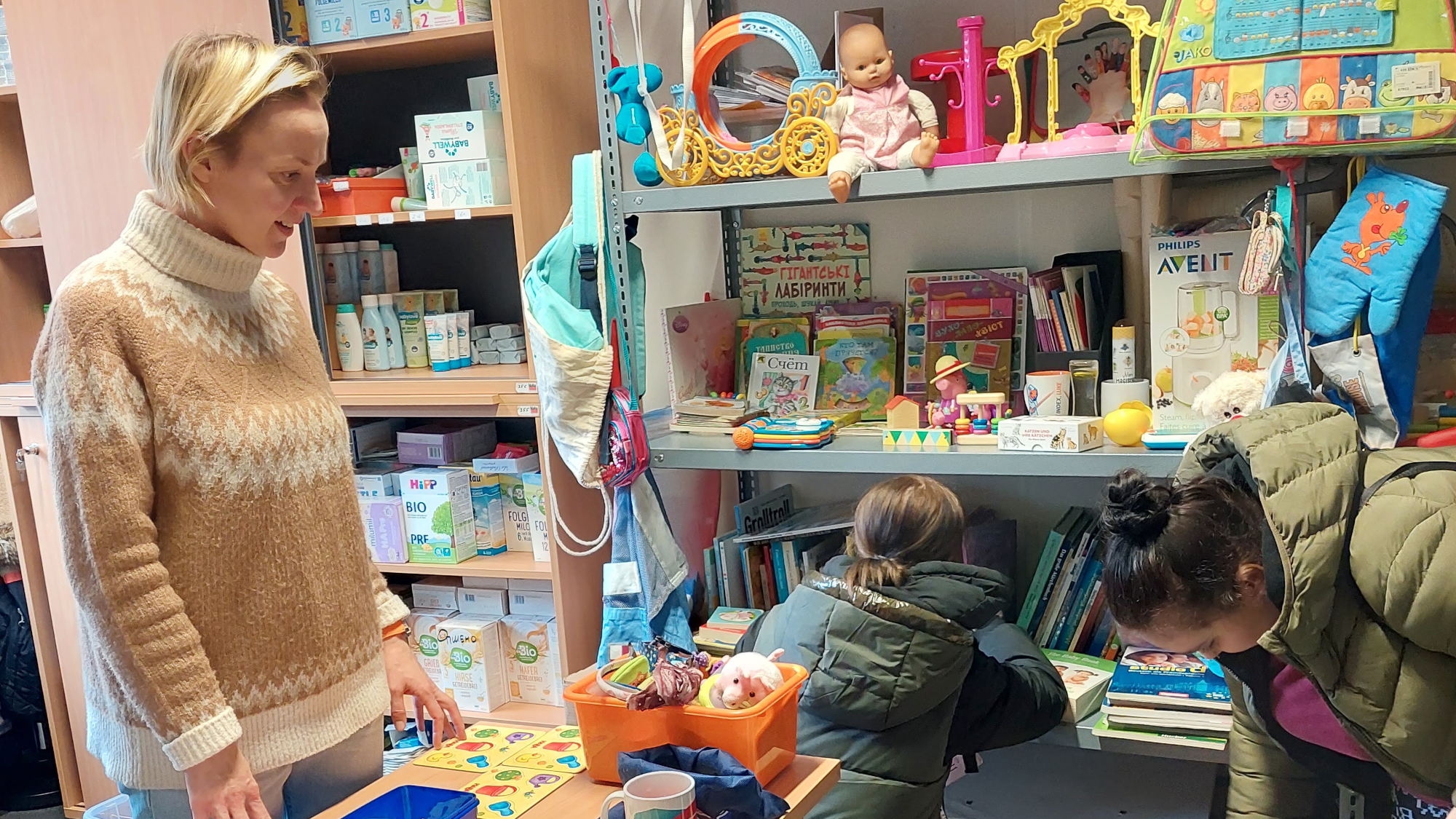 Mütter suchen Bücher und Kinderkleidung für ihre Kleinen aus