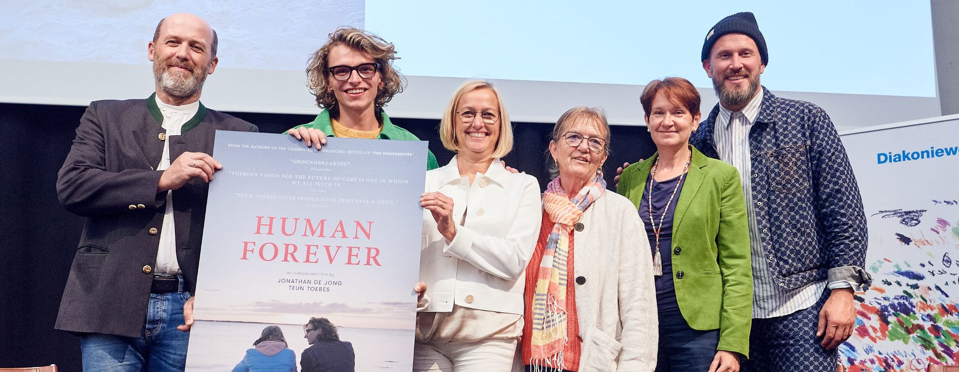 Gruppenfoto: v.l.n.r.: Manfred Schmidhuber (Leitung Haus für Senioren Wels Diakoniewerk), Teun Toebes (Protagonist), Daniela Palk (Vorständin Diakoniewerk), Frau Kappel (Pflegende Angehörige), Petra Rösler (Sozialexpertin Diakonie), Jonathan de Jong (Filmemacher). Fotocredit: Mathias Lauringer/Diakoniewerk