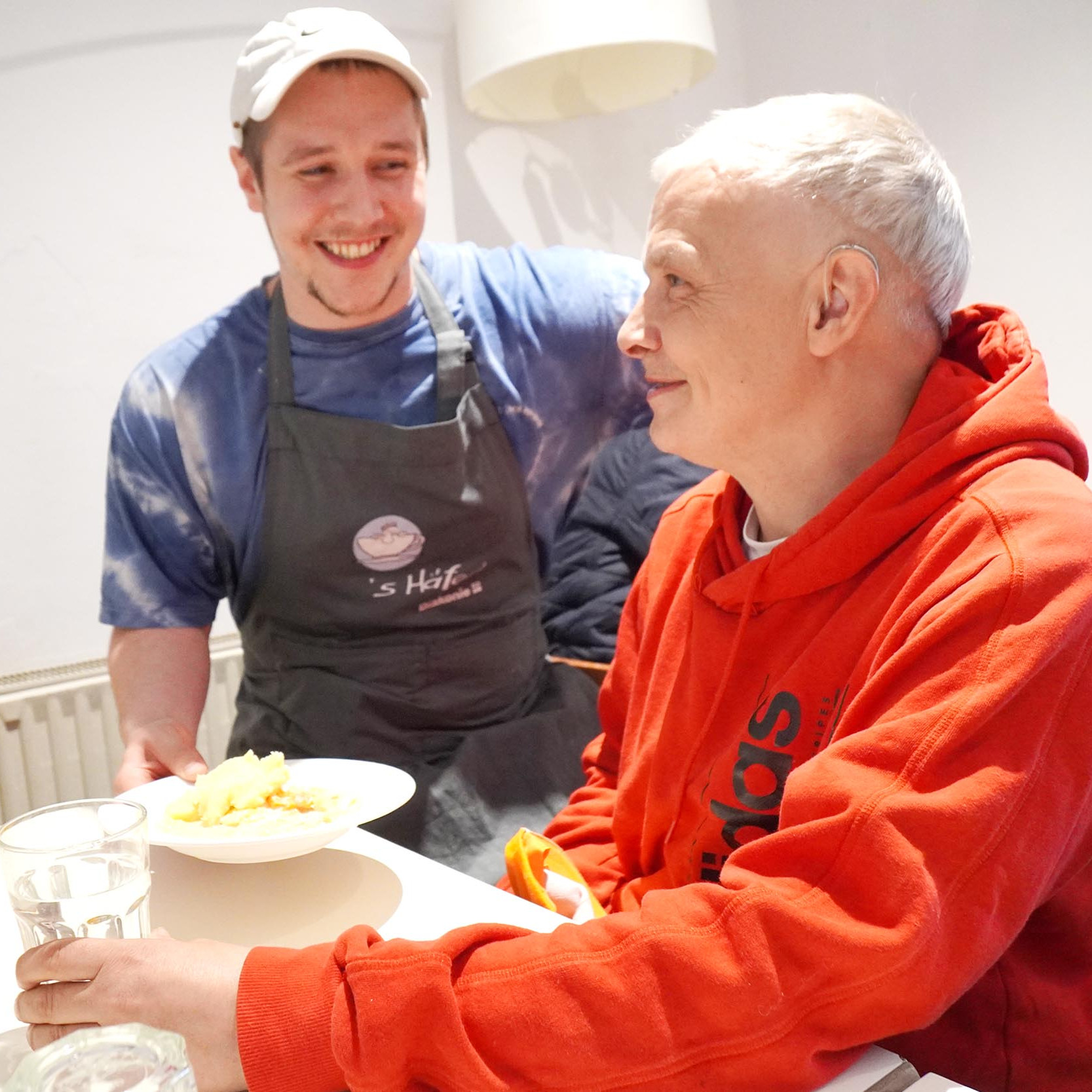 Foto eines Koches der einem Gast ein Teller mit Essen überreicht