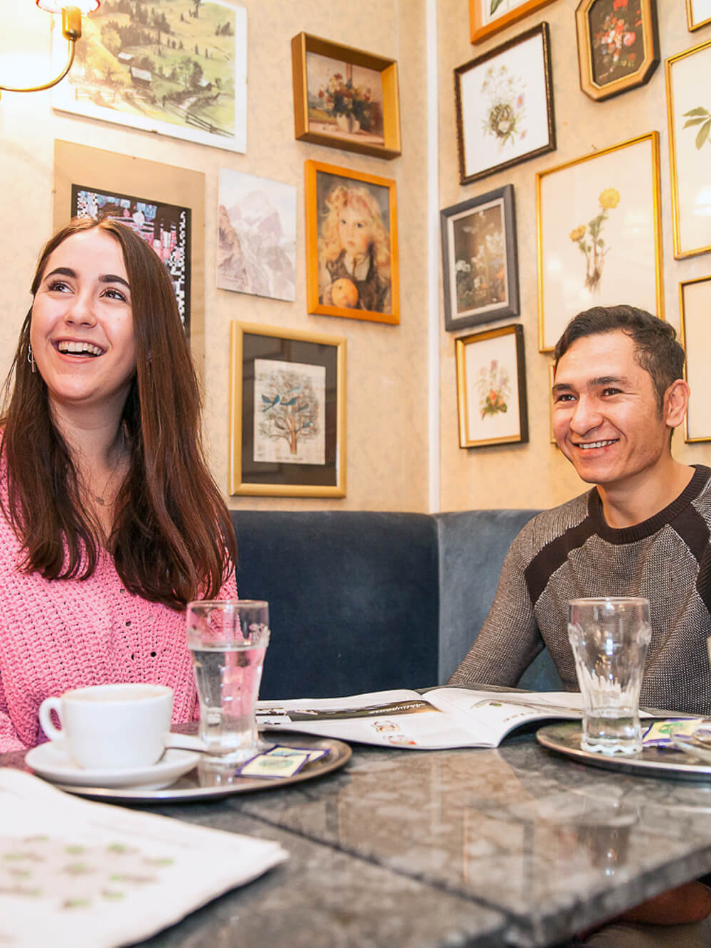 Eine junge Frau und ein junger Mann unterhalten sich bei Kaffee in einem Kaffeehaus