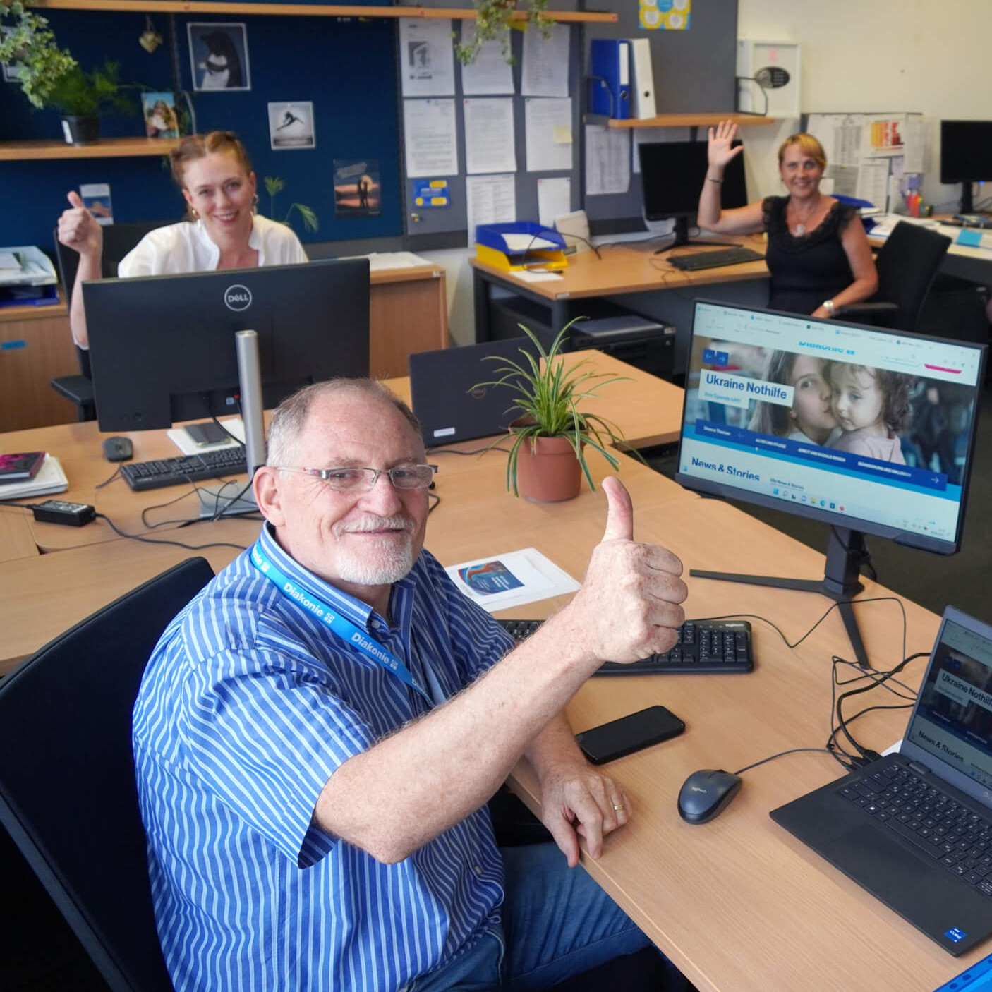 Mitarbeiter:innen der Diakonie winken in die Kamera.