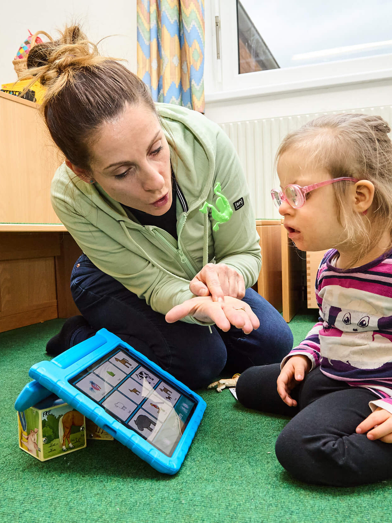 Eine Frau und ein junges Mädchen mit einem Tablet für Unterstützte Kommunikation.