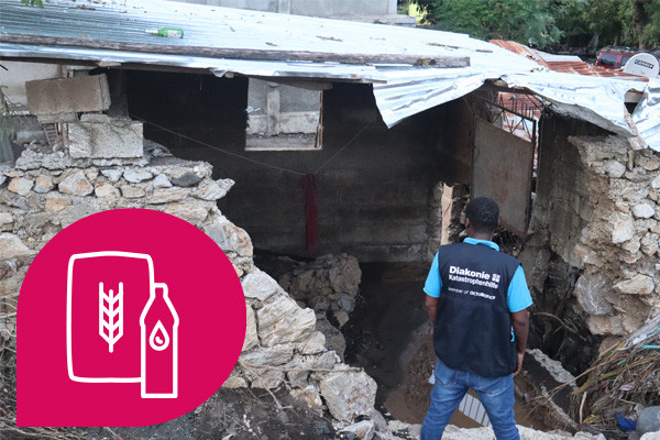 Haus, das von Sturm schwer beschädigt wurde. Mann steht davor und schaut es an.