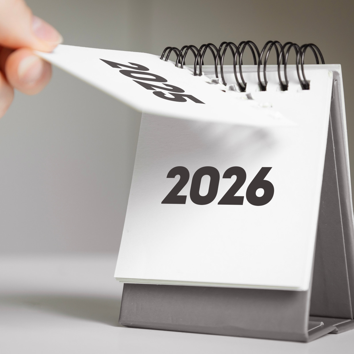 Eine Hand ändert das Kalenderblatt von 2025 auf 2026