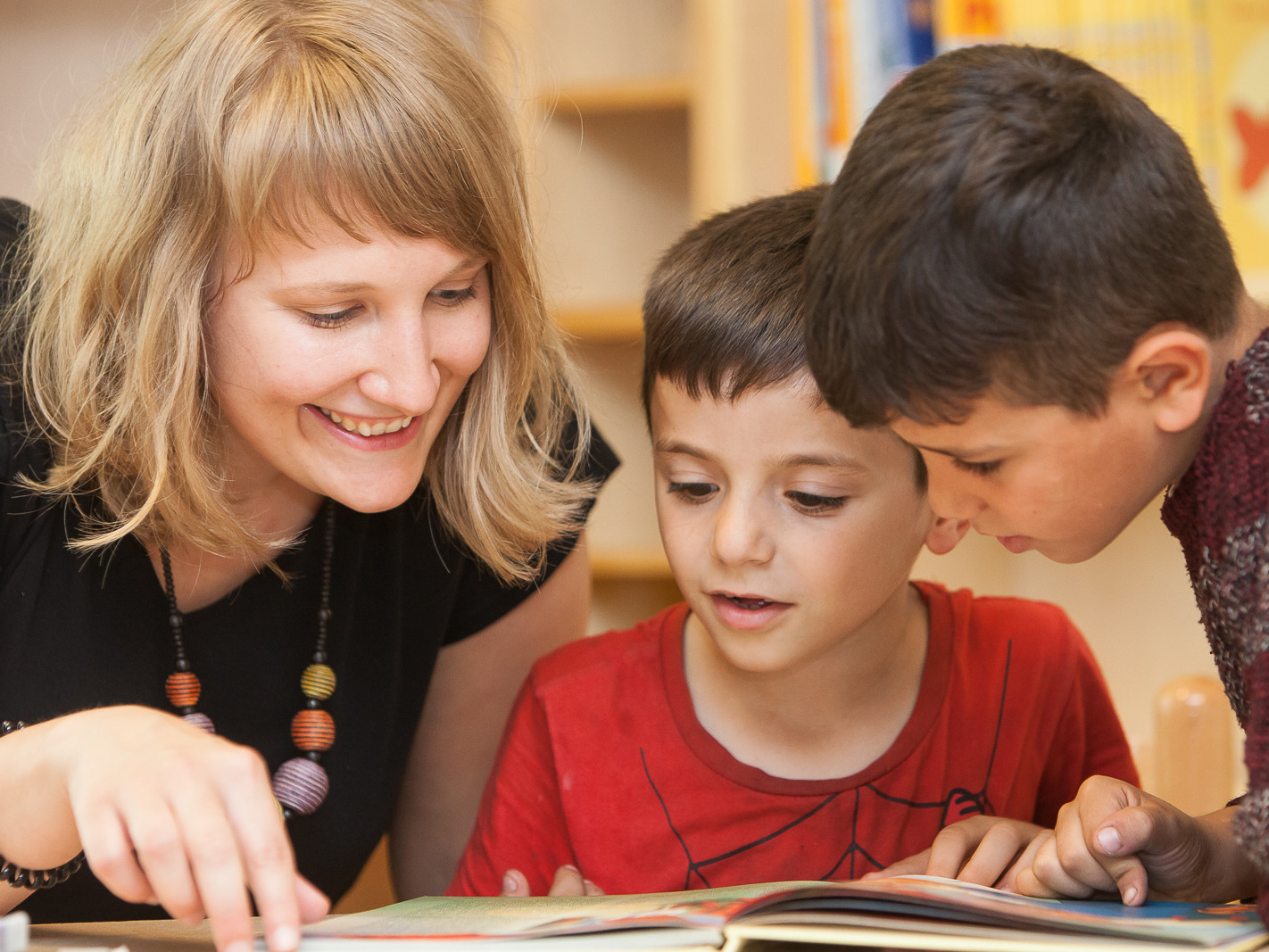 Frau liest mit zwei Kindern in einem Buch