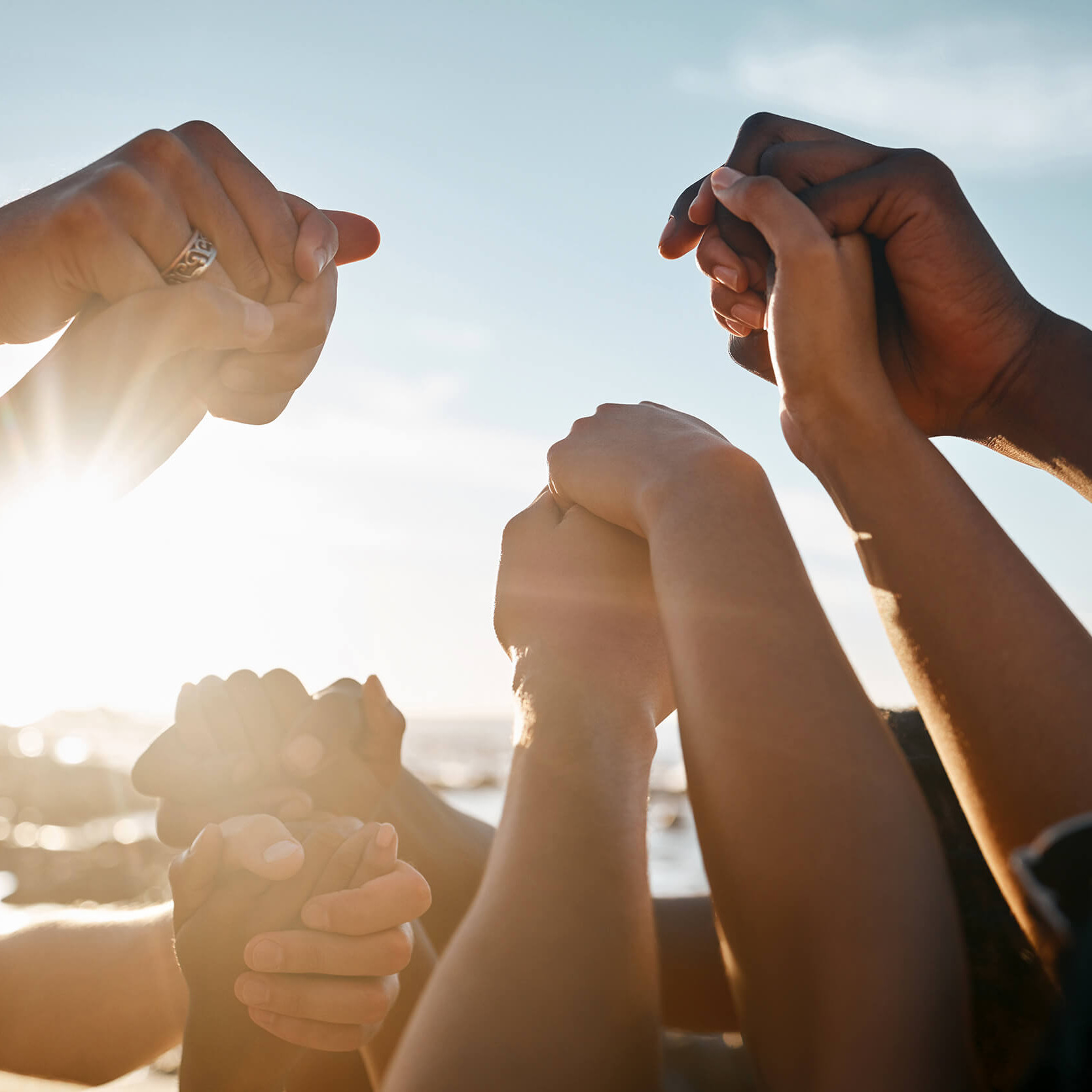 Viele Hände halten einander vor blauem Himmel