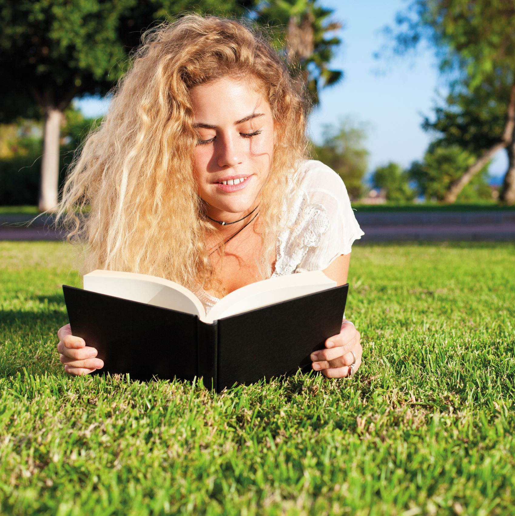 Frau liegt in der Wiese und liest ein Buch