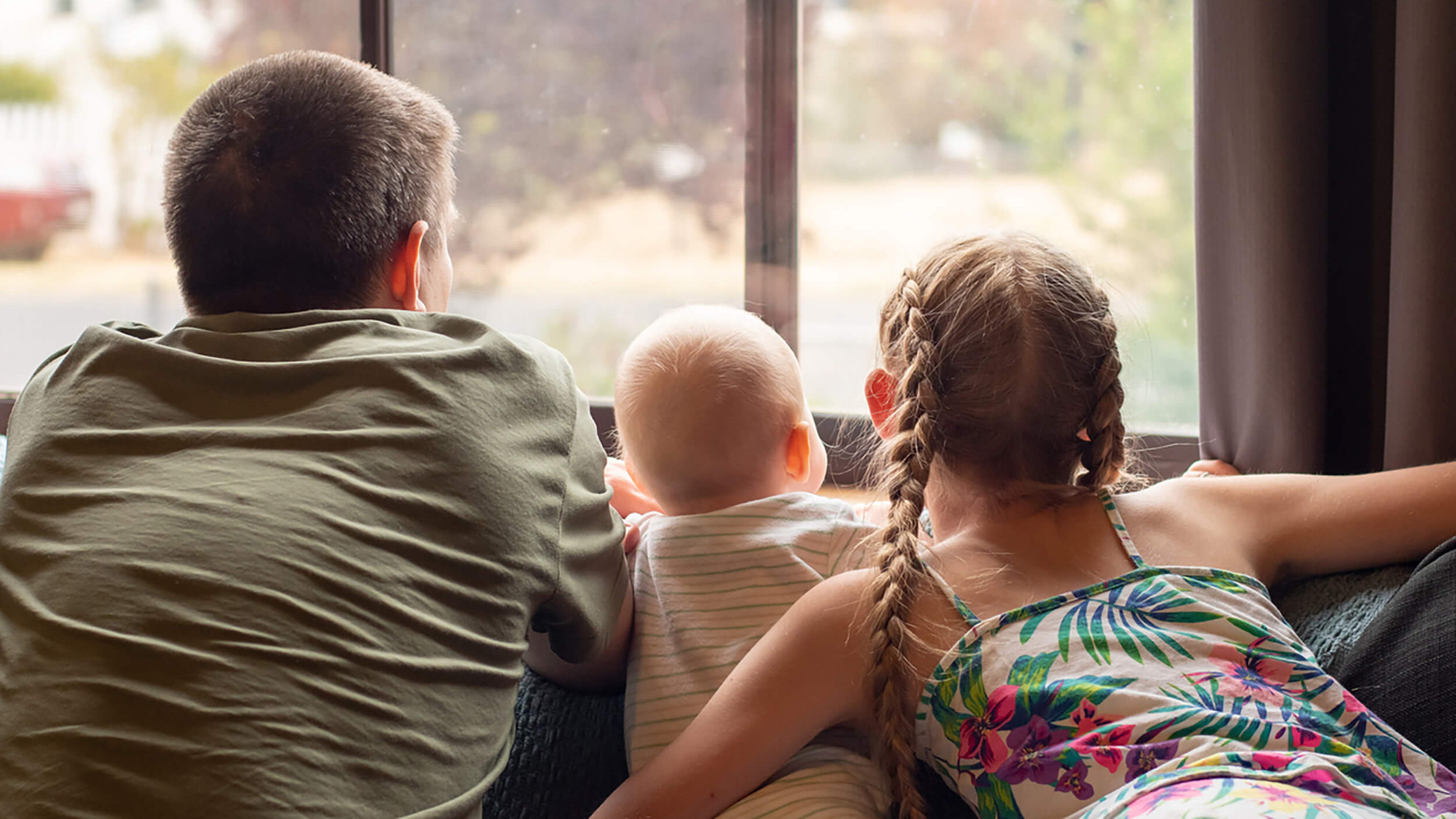 Drei Kinder schauen aus einem Fenster.