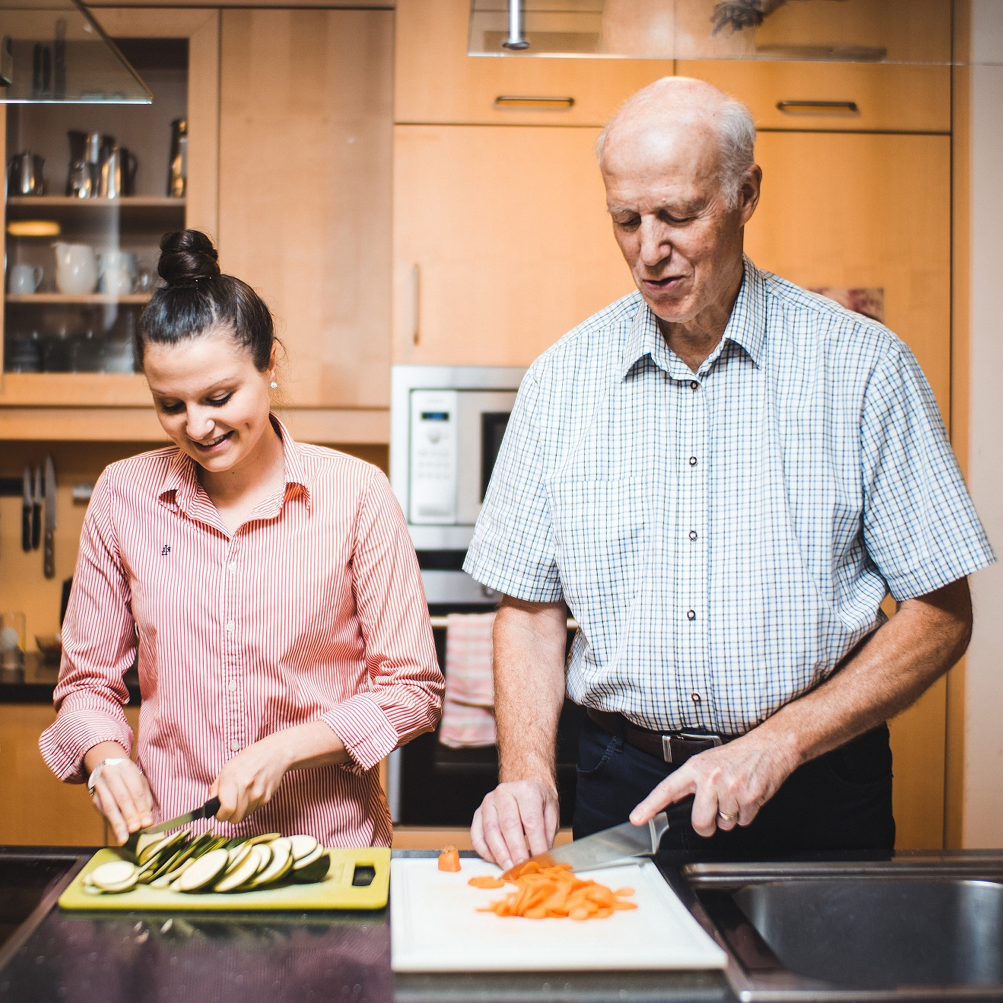 Eine junge Frau und ein älterer Mann kochen gemeinsam.