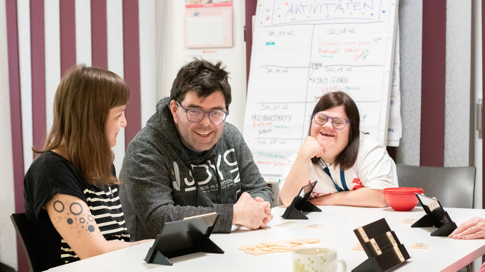 Drei Personen sitzen an einem Tisch - zwei Damen und in der Mitte ein Mann