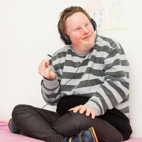 Mann mit Autismus hört Musik und sitzt am Bett