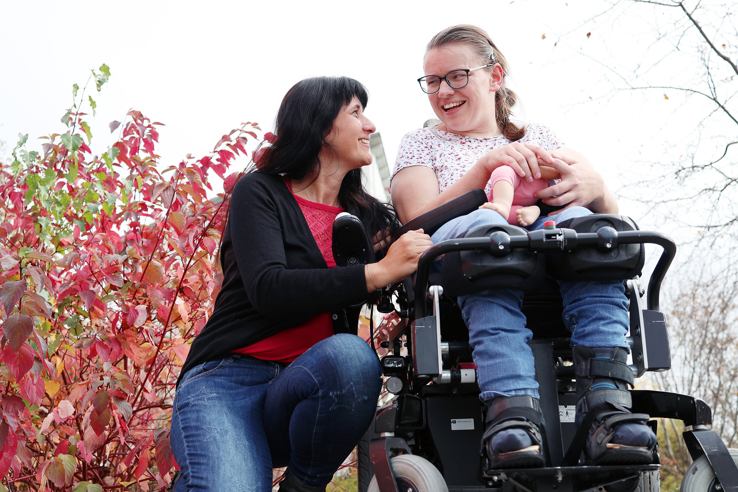 Eine Frau im Rollstuhl und eine Mitarbeiterin der Diakonie in einem Park