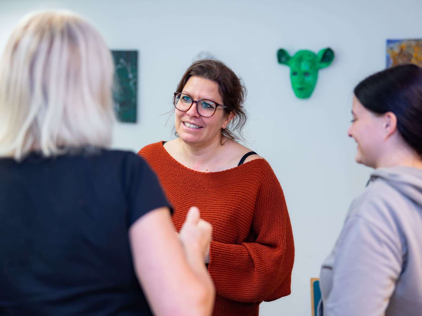 Drei Personen stehen in Klassenzimmer zusammen und reden miteinander