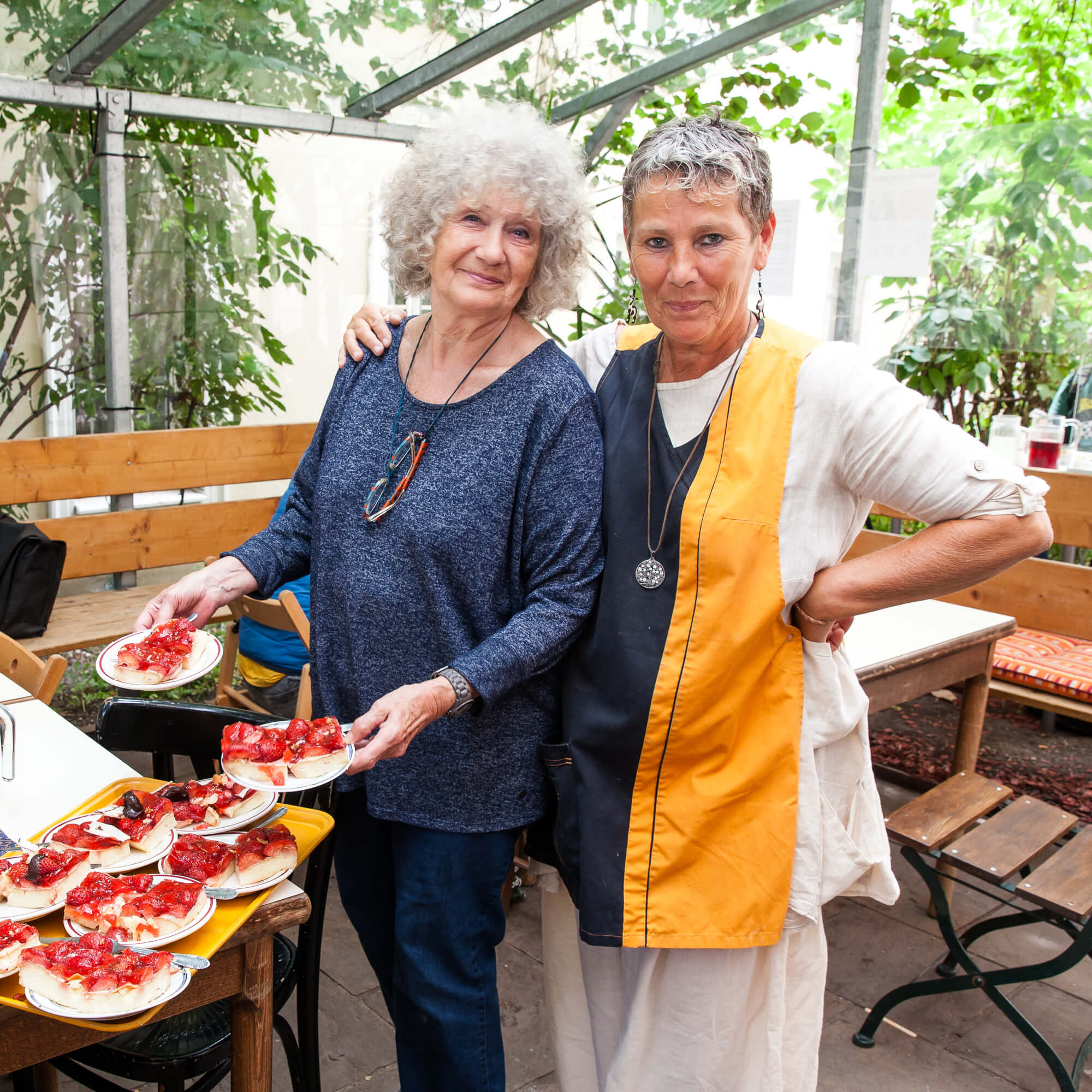 Zwei Frauen servieren Kuchen im Gastgarten des Häferl der Diakonie.