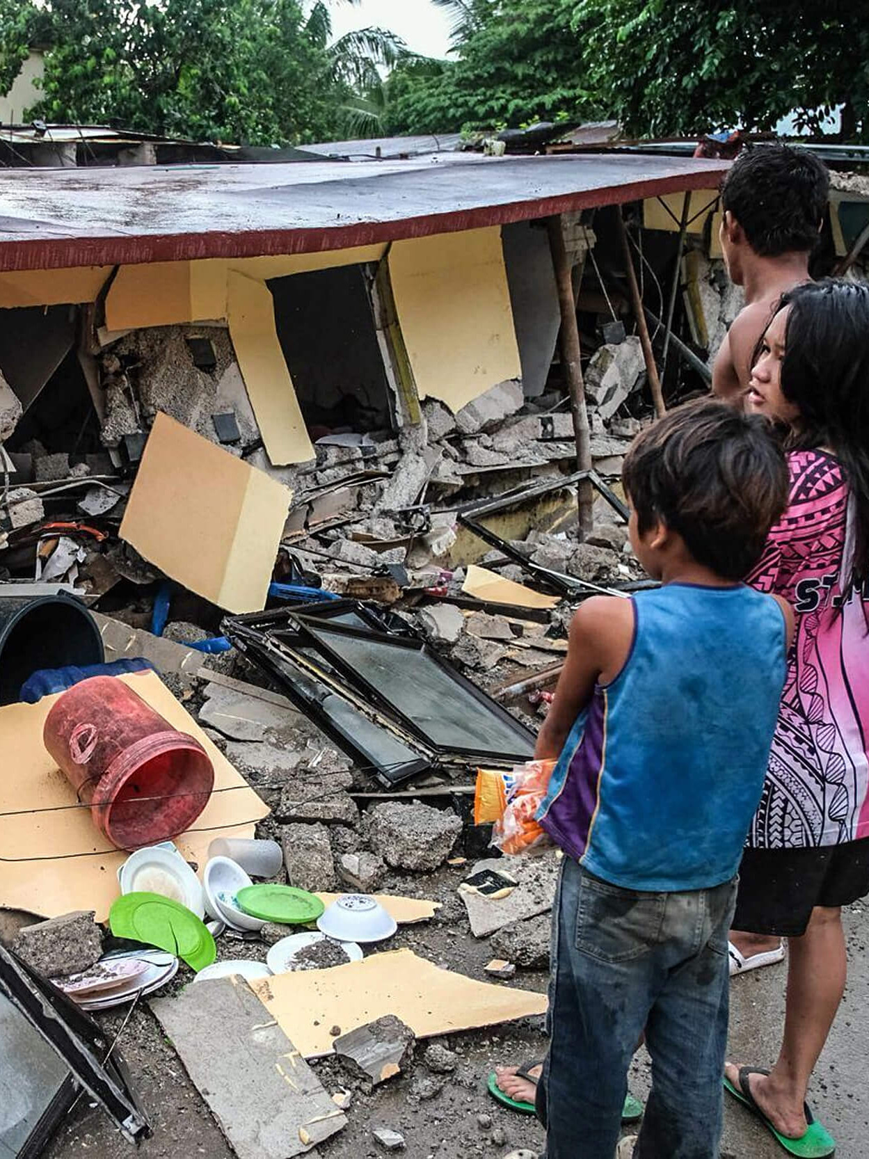 Bewohner:innen vor einem zerstörten Haus auf den Philippinen