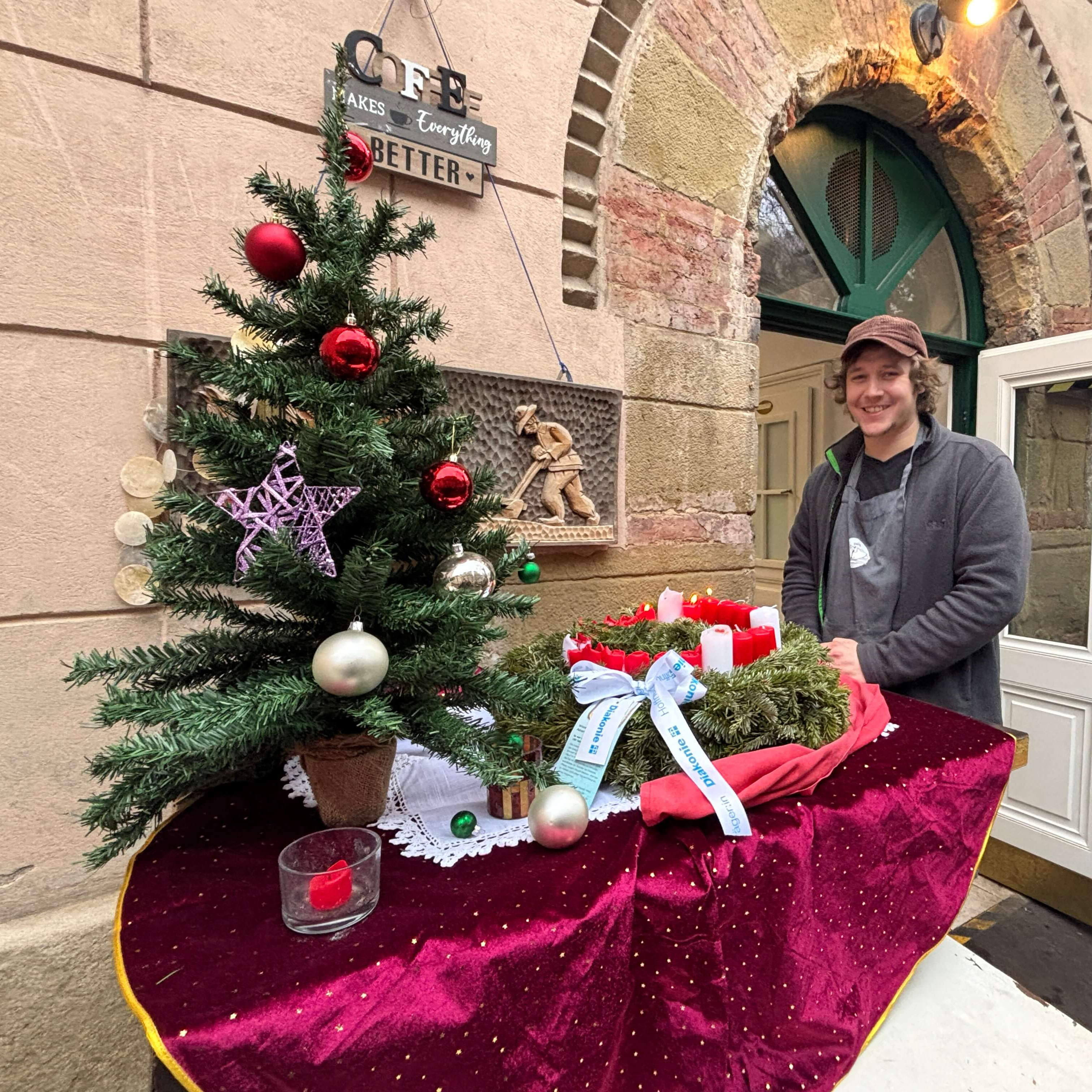 Häferl-Wirt Tobias Riener mit einem Diakonie-Adventkranz vor den öffenen Türen des Häferl.
