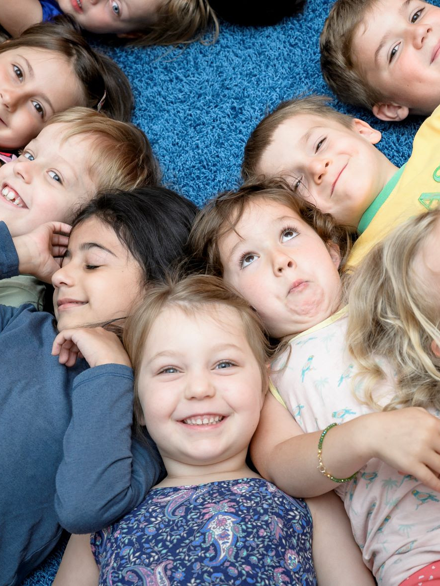 Viele Kinder liegen Seite an Seite am Boden und sind fröhlich