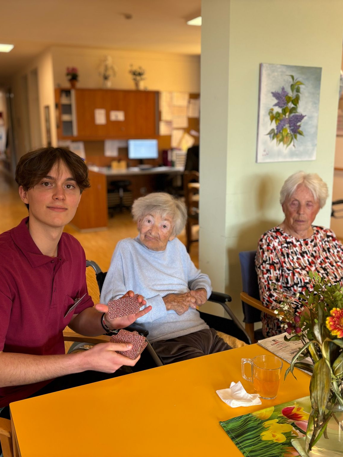 Zivildiener Kevin Schmidt spielt mit Senior:innen im Haus am Ruckerlberg Karten