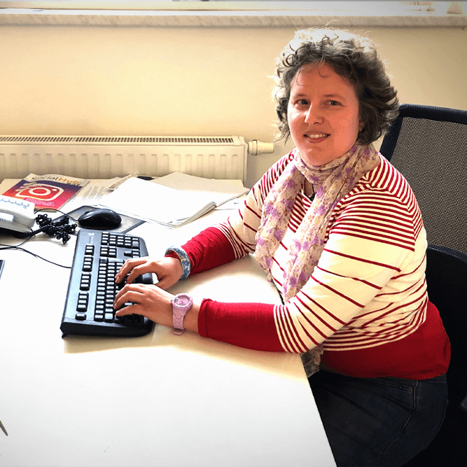 Katja am PC, schaut uns freundlich an