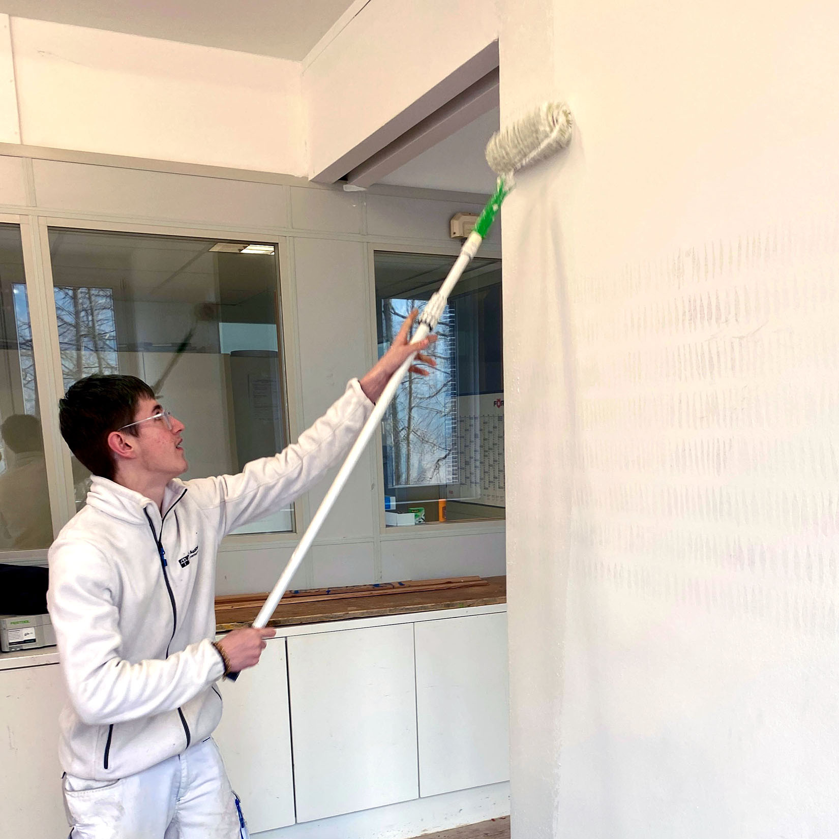 Ein junger Mann streicht eine Wand.