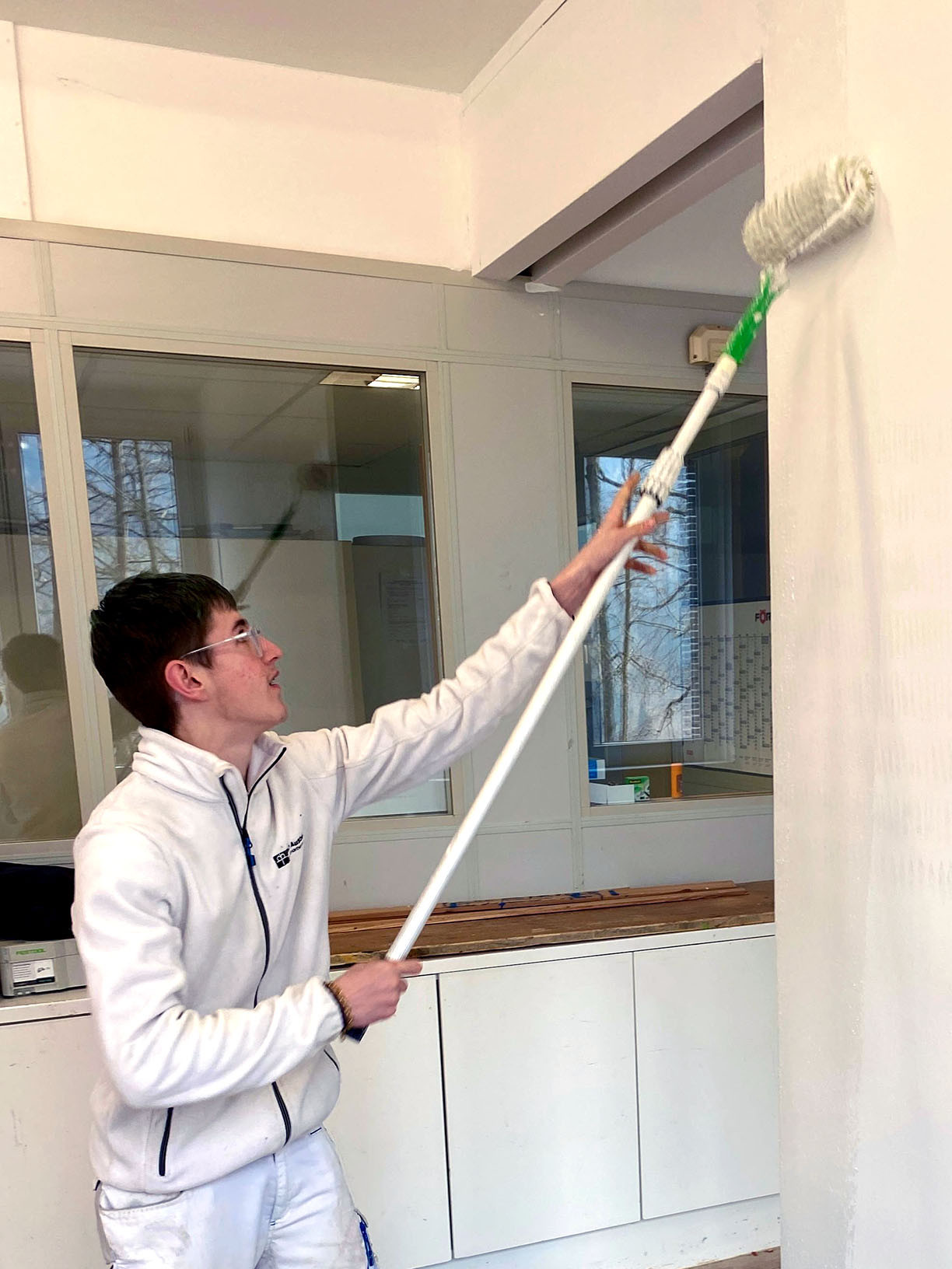 Ein junger Mann streicht eine Wand.