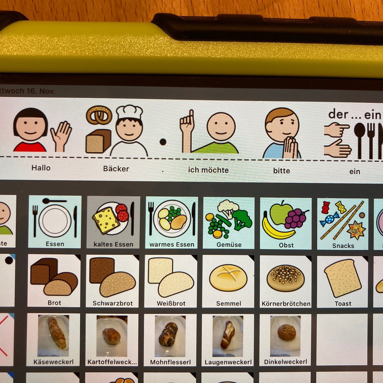 Hannahs IPad mit der besonderen Kommunikations-Software „MetaTalk“.  Man sieht verschiedene Symbole, mit deren Hilfe Hannah beim Bäcker Brot bestellt.