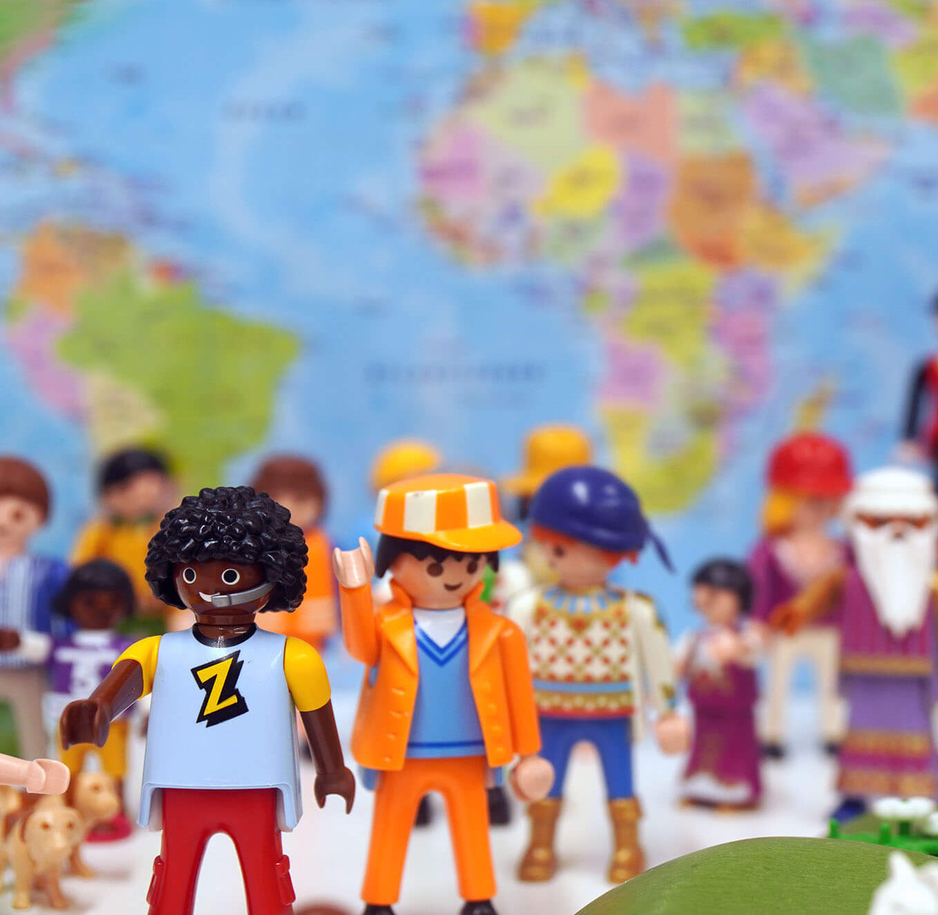 Viele bunte Spielfiguren vor einer bunten Landkarte.