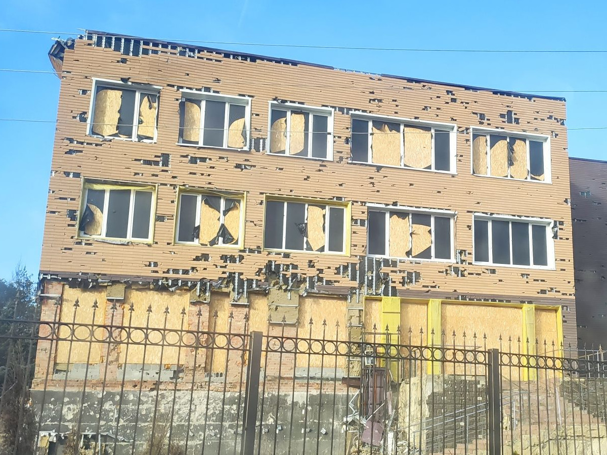 Haus mit Einschusslöchern in der Fassade und zerbrochenen Fenstern