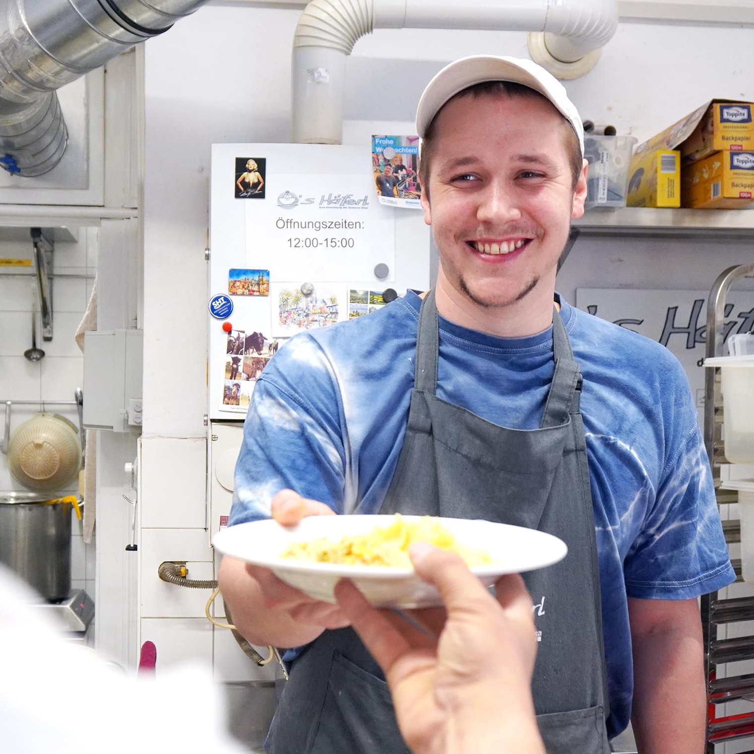Ein Koch überreicht einem Gast sein Essen
