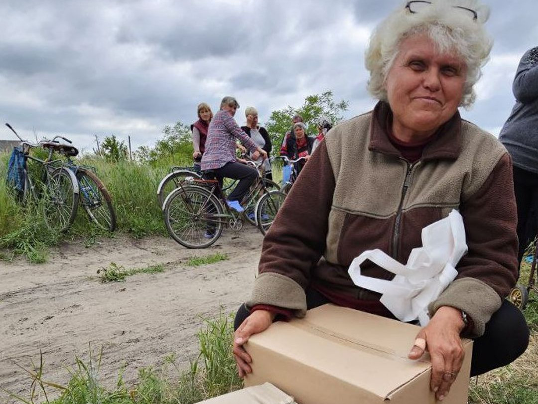 Frau in der Ukraine zeigt Schachteln mit Hygiene-Artikeln, die sie dank Spenden erhalten hat.