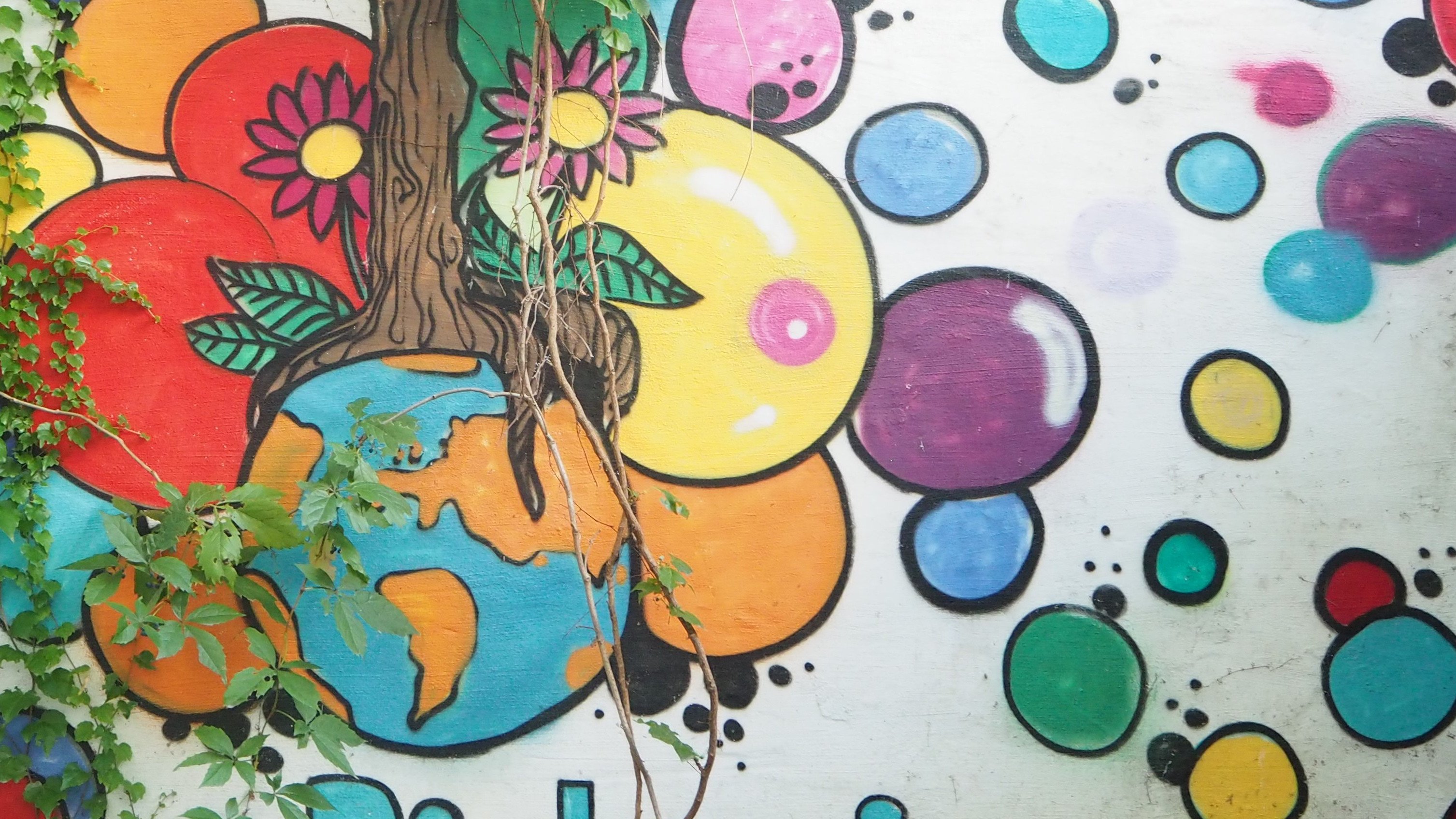 Buntes Graffiti mit einer Weltkugel und bunten Bällen auf einer Mauer