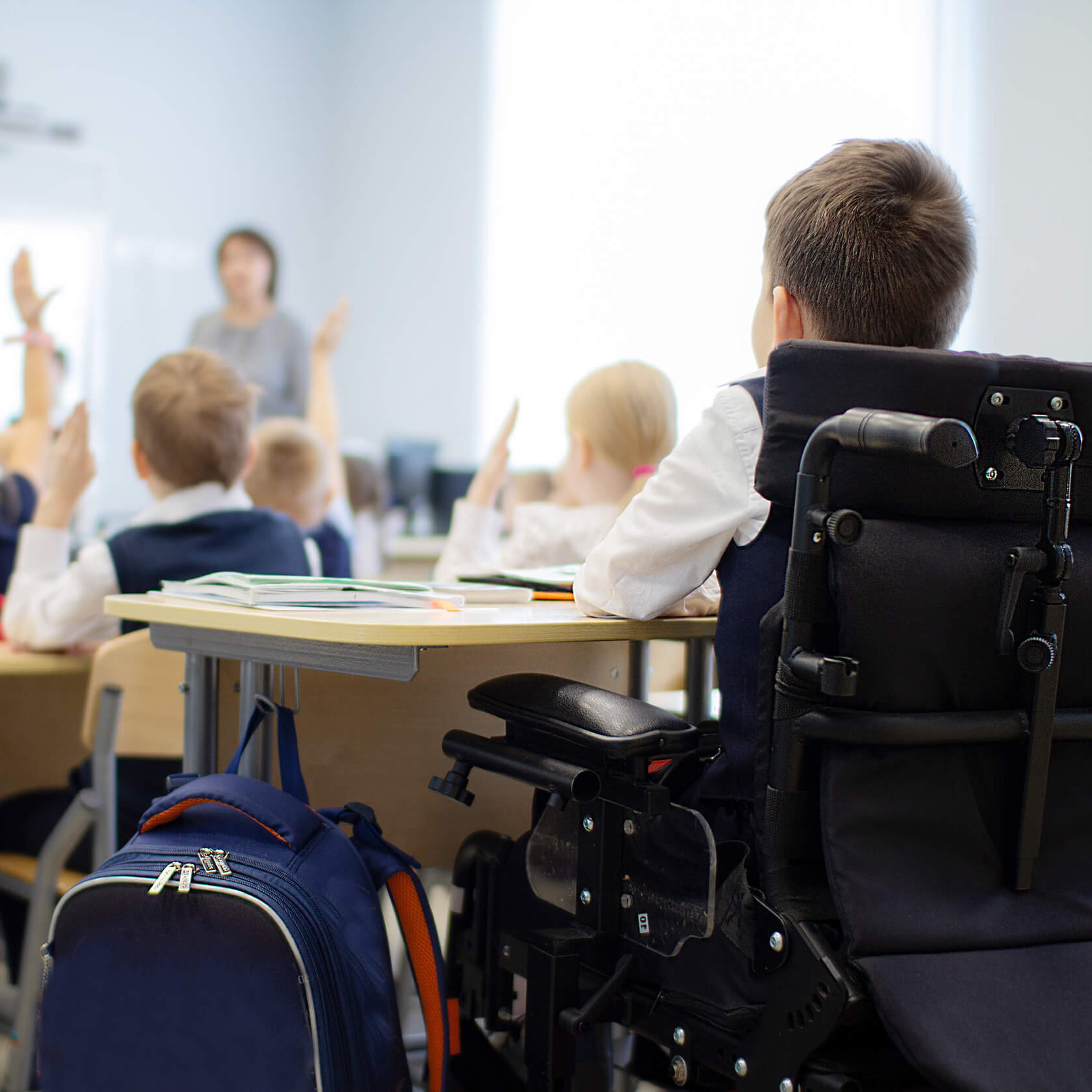 Ein Bub in einem Rollstuhl sitzt gemeinsam mit anderen Kindern in einer Schulklasse.