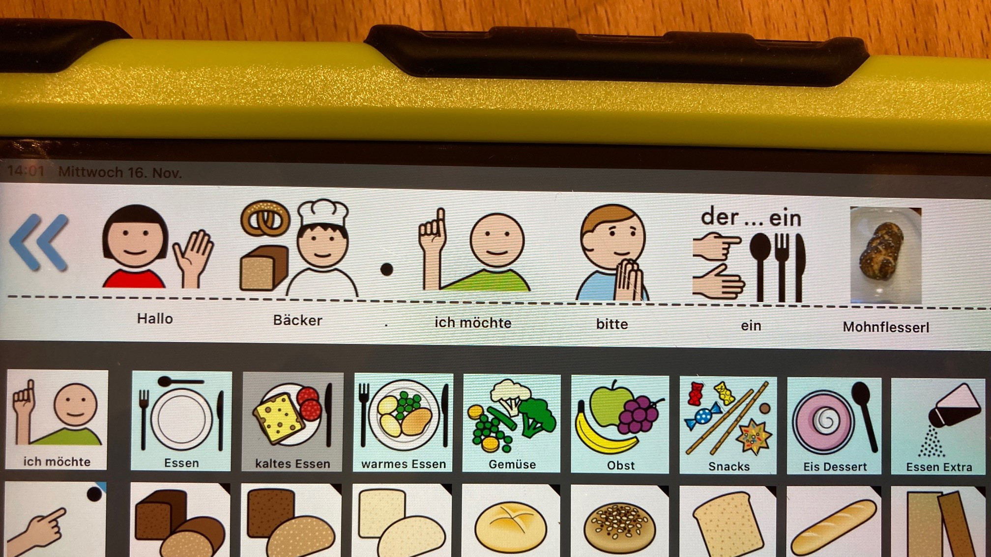 Hannahs IPad mit der besonderen Kommunikations-Software „MetaTalk“.  Man sieht verschiedene Symbole, mit deren Hilfe Hannah beim Bäcker Brot bestellt.