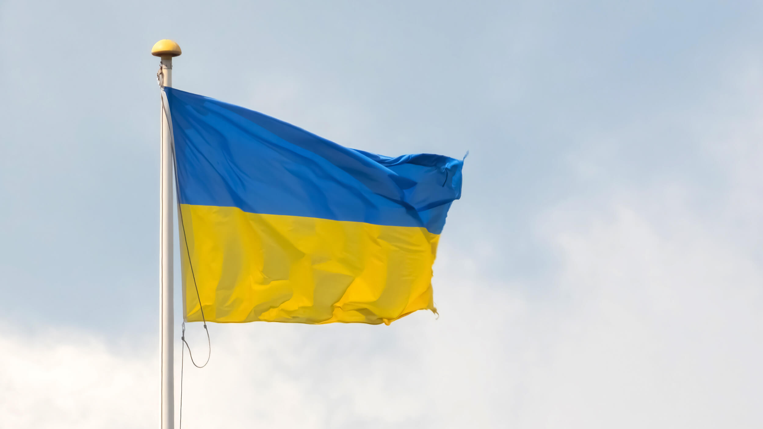 Eine Ukraine-Fahne vor graublauem Himmel.