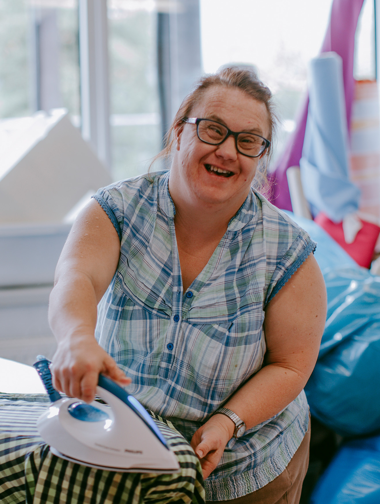Eine Frau bügelt in der Werkstätte und hat Freude an der Arbeit.
